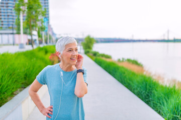 Athlete runner in sportswear relaxing getting inspired. Fitness runner on mobile smart phone app tracking progress listening to music with earphones for fitness motivation.