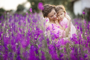 Pretty little girl and her mother with flowers. Family outdoors