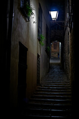 Naklejka na ściany i meble Alley with a staircase going up illuminated by a slight light from a lamppost