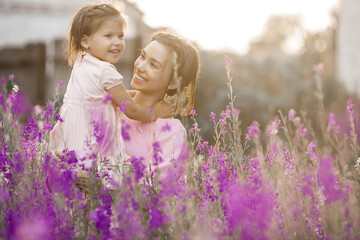 Pretty little girl and her mother with flowers. Family outdoors