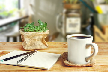Education Workplace with coffee cup ,notebook and small plant on coffee shop background.
