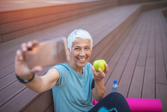 Senior Woman Making A Selfie Before Jogging. Female Jogger Relax After Exercising And Taking Photographs. Active Senior Woman Posing For A Selfie Image During Workout