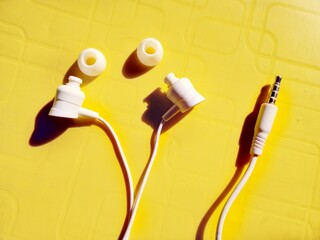  White ear buds with removed rubber  fore head & jack pin on a yellow background