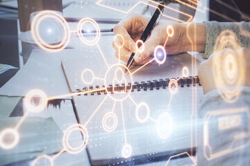 Social network theme hologram over hands taking notes background. Concept of global international people connect. Double exposure
