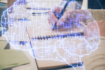 Double exposure of writing hand on background with brain hologram. Concept of learning.