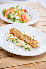 chicken kebab with rice and salad on the wooden background