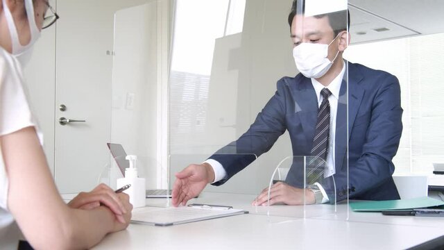 アクリルパーティション越しに話すビジネスマン　感染対策　60pスローモーション