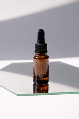 cosmetic oil in glass bottle on white background with trendy shadows