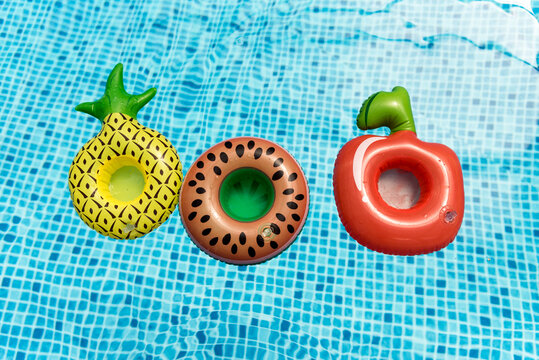 Inflatable circle fruits pineapple,  apple, watermelon,  floating on surface of Summer Pool with blue faience 