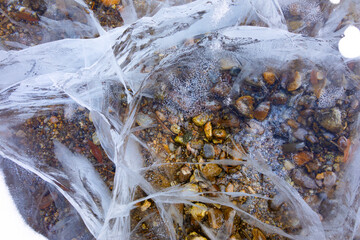 Pebbles under the crystal clear river ice
