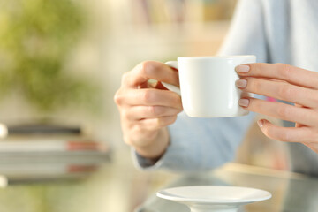 Woman hands holding coffee cup on a desk at home