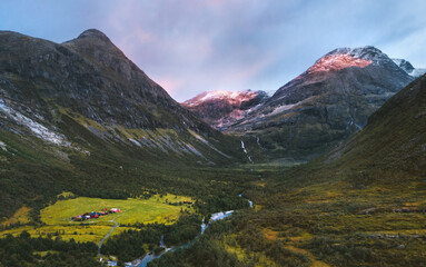 Fototapeta premium Aerial view sunset mountains valley and farm houses in Norway landscape travel beautiful destinations Jostedalsbreen national park.