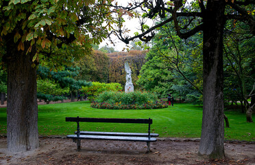 View of a garden in a park with a bench to sit on