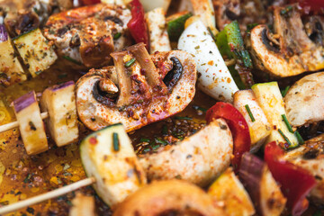 Vegan barbecue skewer. Vegetarian party food with very spiced eggplant, onion and pepper mushrooms. Focus on one point and the rest blurred