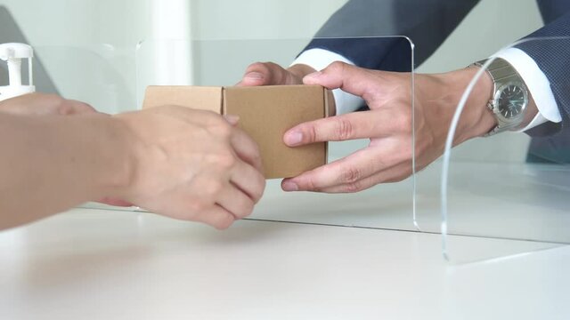 アクリルパーティション越しに荷物を受け渡す人々　感染対策　60pスローモーション