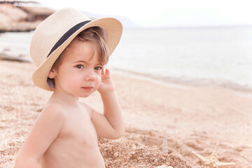 Portrait of caucasian happy baby (boy) in the hat at the beach.