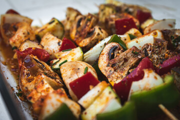 Vegan barbecue skewer. Vegetarian party food with very spiced eggplant, onion and pepper mushrooms. Focus on one point and the rest blurred