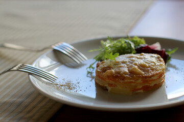 Puff omelet with cheese and salad on a white plate on a table in a restaurant