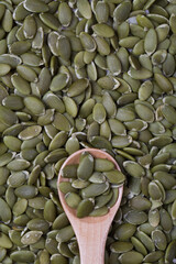 top view of pumpkin seeds in wooden spoon.