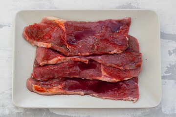 raw meat with spices on grey dish