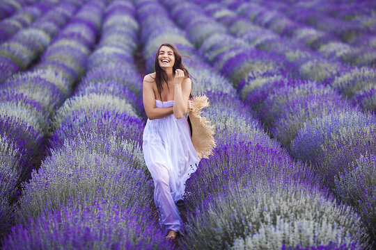 Young woman running in the lavender field. Beautiful woman on summer floral background