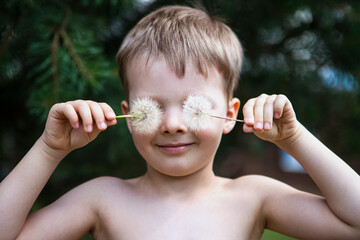 The boy closes his eyes with dandelions