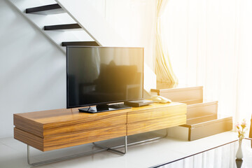 Smart TV wide screen stand on cabinet wooden in the modern living room with sunlight effect. Concept of less is more interior design