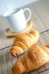 Two fresh croissants and cup of coffee on dark stone table
