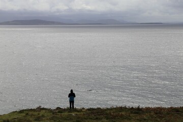 A person quietly enjoying the view across Clew Bay from the Spanish Armada Viewpoint on the Wild Atlantic Way, County Mayo, Ireland.