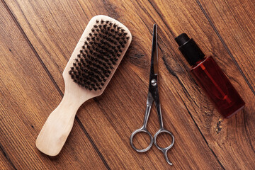 Beard grooming accessories on a luxury wooden surface. Wooden bristle brush, bottle of oil and...