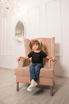 The little girl sits on a chair.