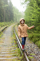 Cute red hair girl walking on railway alone, she is sad. The only one way to travel in coronavirus quarantine time. Rainy weather.