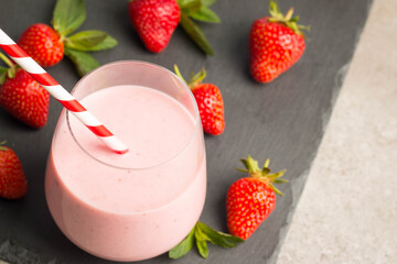 Glass of fresh strawberry milkshake, smoothie and fresh strawberries on pink, white and wooden background. Healthy food and drink concept.