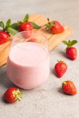 Glass of fresh strawberry milkshake, smoothie and fresh strawberries on pink, white and wooden background. Healthy food and drink concept.