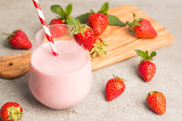 Glass of fresh strawberry milkshake, smoothie and fresh strawberries on pink, white and wooden background. Healthy food and drink concept.