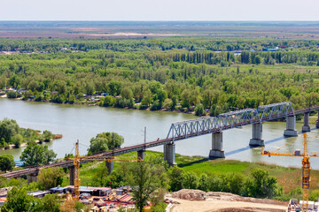 Fototapeta premium The railroad bridge over river among green forest. Don river, Green Island, Rostov-on-Don, Russia