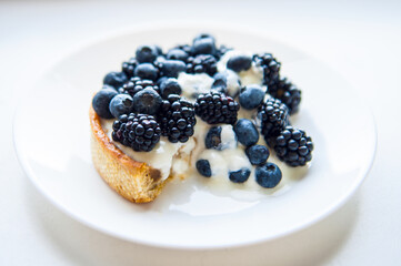 Pastry cake with blueberry and blackberry and yogurt on white plate. Delicious pie