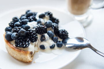 Pastry cake with blueberry and blackberry and yogurt on white plate. Delicious pie and coffee