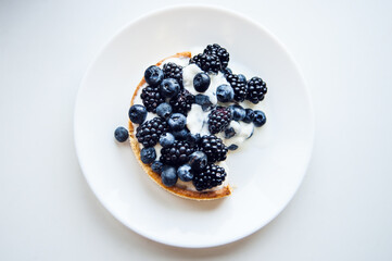 Pastry cake with blueberry and blackberry and yogurt on white plate. Delicious pie