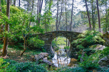 View of the Half moon stone bridge among green trees in the forest in Little rock, USA