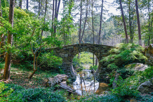 View of the Half moon stone bridge among green trees in the forest in Little rock, USA
