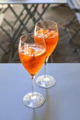 Italian aperitif aperol spritz with ice and a slice of orange in  large round glasses on the blue table in a bar in Italy