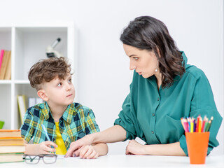 Mother helps her young son doing homework at home