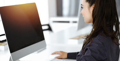 Business woman using computer at workplace in sunny office. Working for pleasure and success