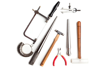 Different goldsmiths tools on the jewelry workplace. Desktop for craft jewelry making with professional tools. White background. 