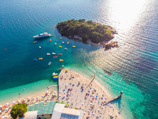 Aerial view of a beautiful white sand beach with turquoise water and relaxing people on a sunny day. Ksamil, Albania.