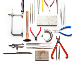 Different goldsmiths tools on the jewelry workplace. Desktop for craft jewelry making with professional tools. White background. 