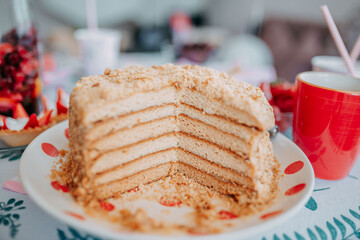 Home made honey cake on birthday party. Kid's birthday table with sweets, candies, cakes, and strawberries. Birthday party food.