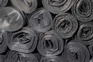 Rolls of plastic bags. Textured background for wallpaper. Lots of black rolled up bags for construction waste.