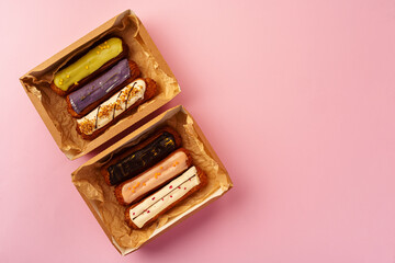 Box with fresh eclairs on pink background